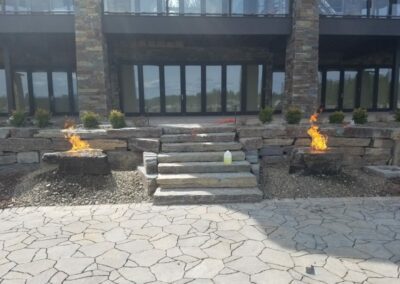 house with stone staircase and two circular firepits with active flames