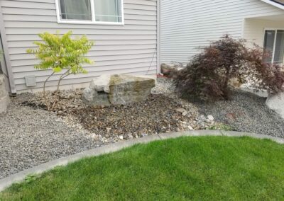 small rock garden with newly plated trees and rock fountain
