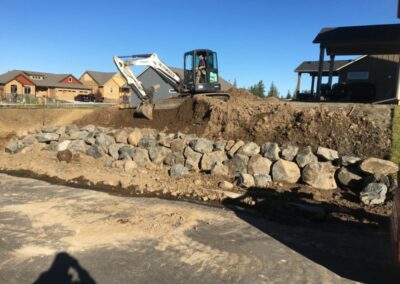 landscaping using heavy machinery to construct rock wall