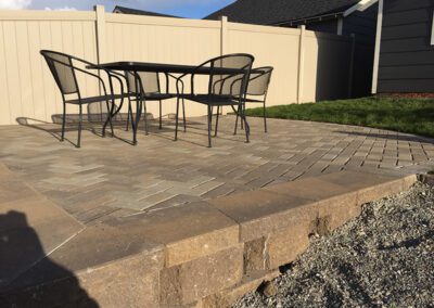 patio chairs on stone pavement in corner of yard