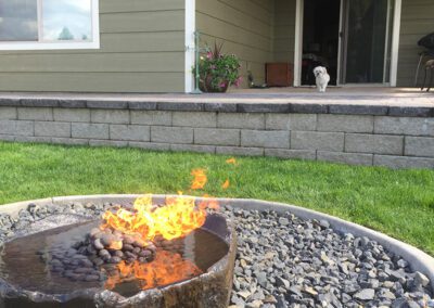 small white dog on patio facing circular firepit