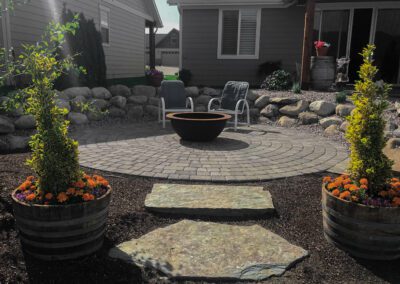 backyard with Circular stone patio with center firepit and chairs