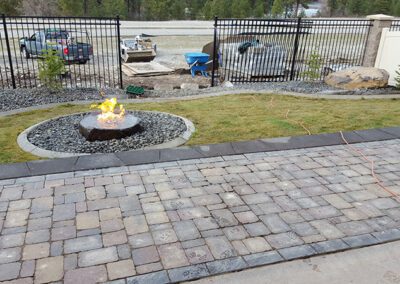 circular firepit with active fire next to stone pathway
